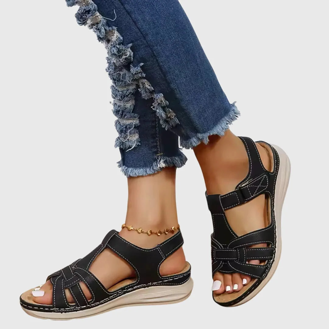 Pair of black woven leather gladiator sandals with cushioned sole, shown from the side on model's feet