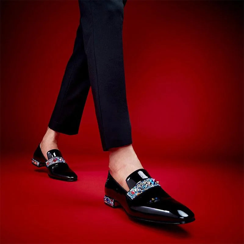 Model walking in black patent loafers with crystal strap detail, paired with slim black tailored trousers
