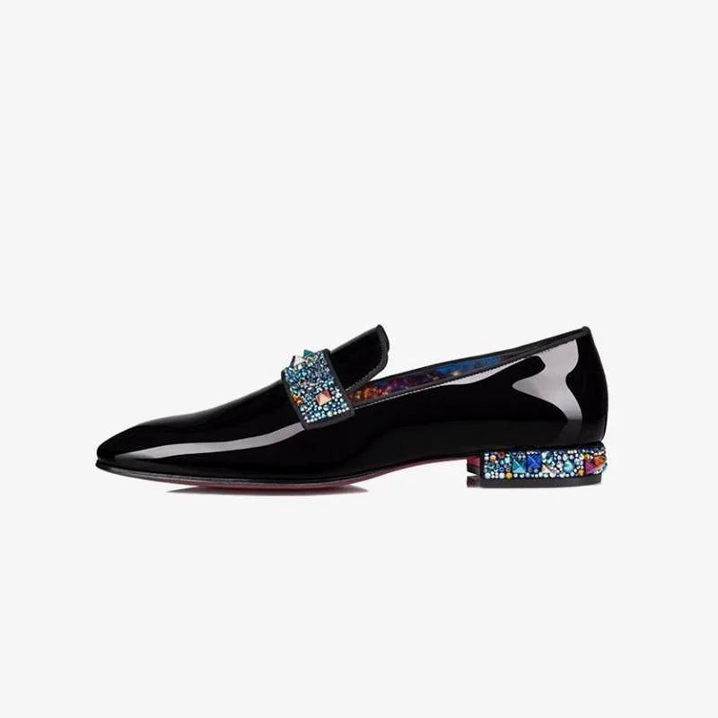 Side profile of a black patent leather loafer showing the pointed toe and multicoloured crystal heel