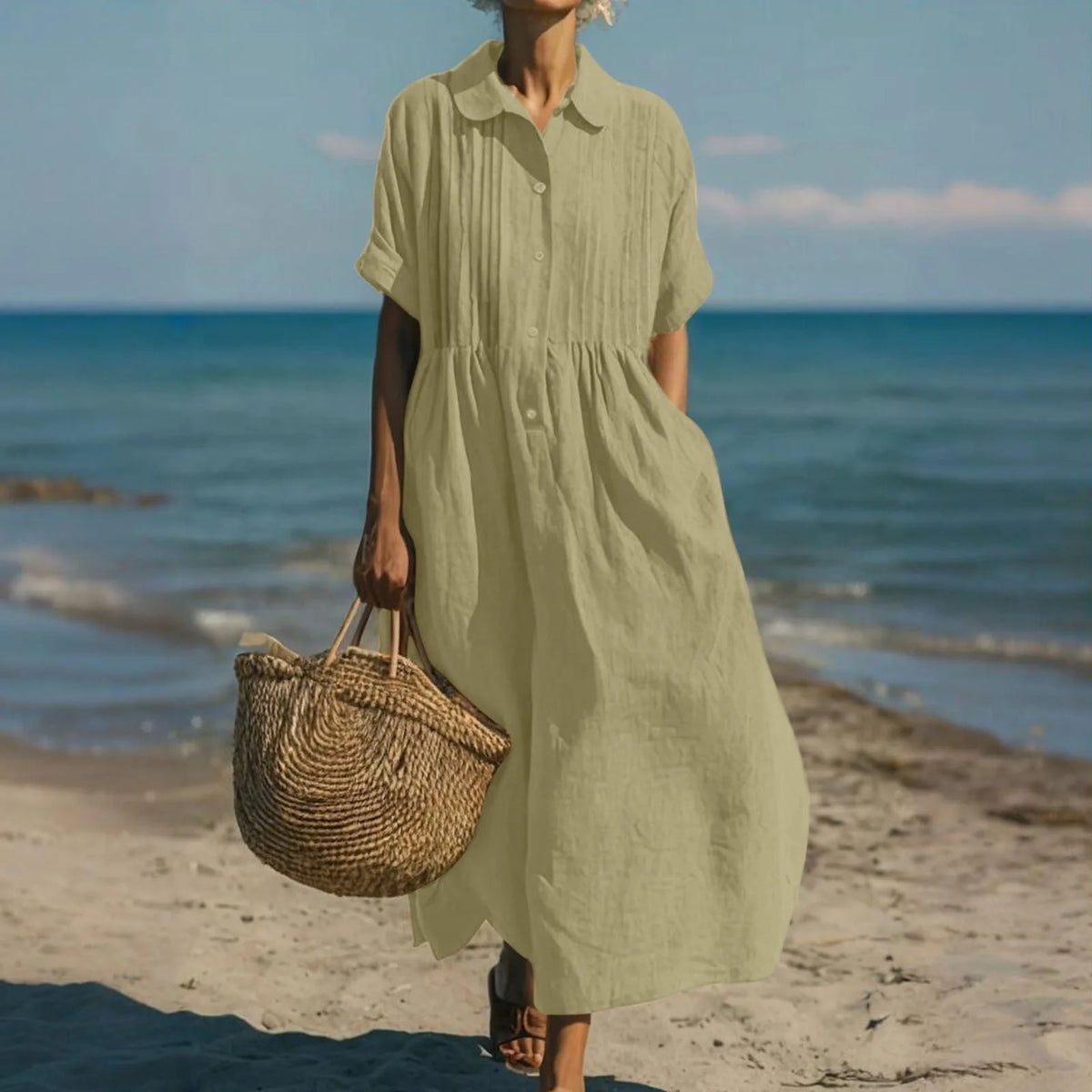 Model in motion on the sand wearing the dress, highlighting the short folded sleeves and loose gathered skirt