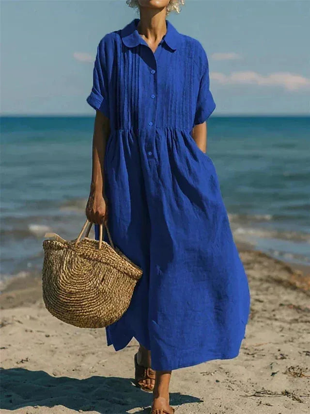 Close-up beach shot of the maxi shirt dress in a deeper blue shade, showing the collar and pintuck bodice