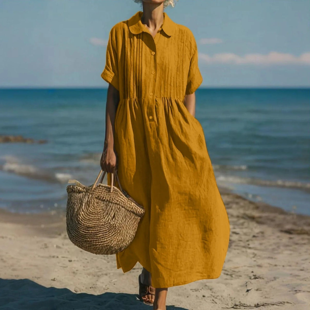 Model on the beach wearing the dress in a warm orange tone, showing the relaxed A-line silhouette