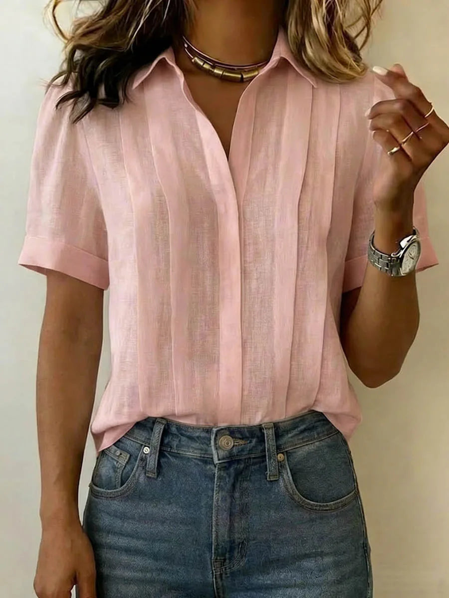 Soft pink pleated linen blouse with V-neckline and folded cuffs, styled with a gold choker necklace