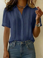 Navy blue pleated linen blouse with classic collar and folded short sleeves, paired with light wash denim