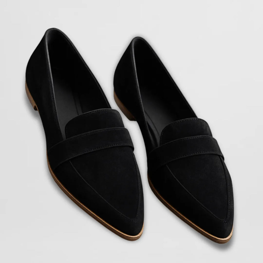 Black suede pointed-toe loafers with penny strap detail, side angle on a plain background