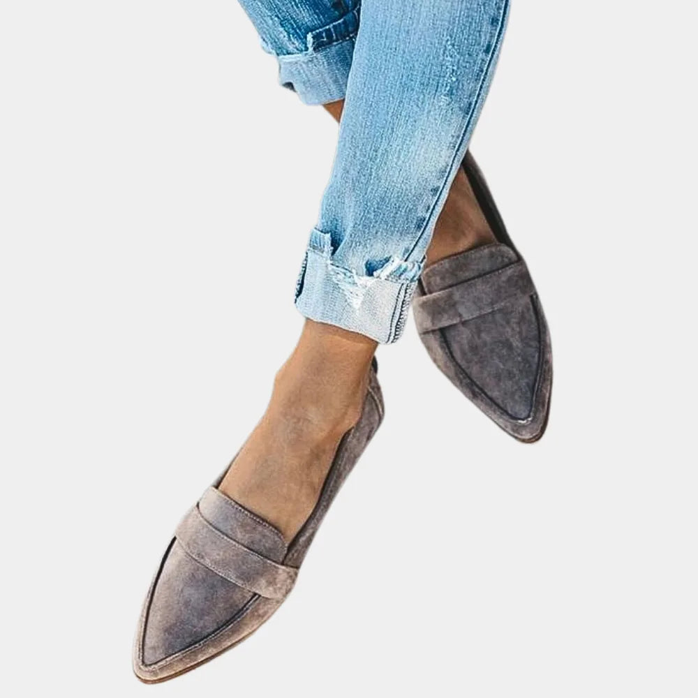 Side profile of grey suede pointed loafers with woven panel detail, paired with cuffed jeans