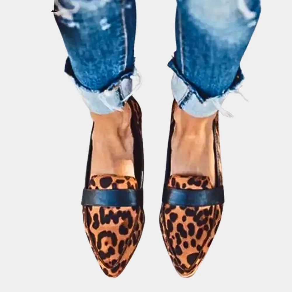 Front view of leopard print pointed loafers with black panel trim worn with rolled-up denim