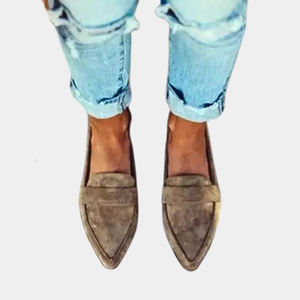 Front-facing close-up of khaki suede pointed loafers with classic penny strap detail