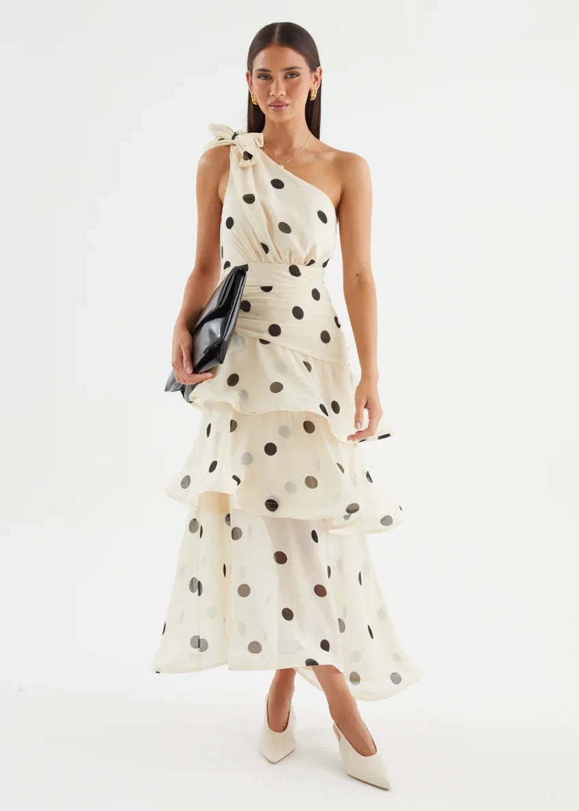 Front view of the dress paired with a black clutch, showing the ruched waist and tiered ruffle skirt