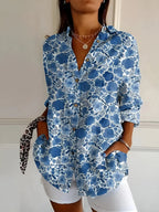 Blue and white floral blouse with a watercolour-style bloom print, buttoned low with a pointed collar