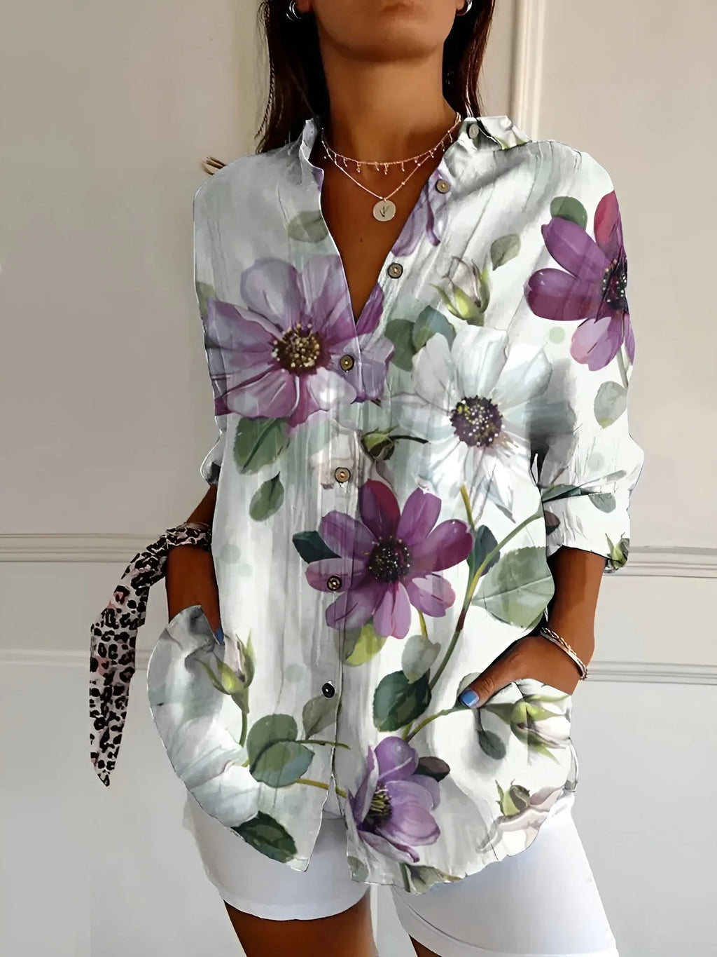 Pale blouse covered in large purple and white watercolour flowers with soft green leaves