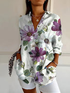 Pale blouse covered in large purple and white watercolour flowers with soft green leaves
