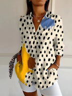 Detail view showing the rolled-up cuff, button placket and relaxed drape of the printed blouse fabric