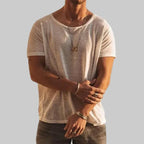 Man wearing a white lightweight crew neck T-shirt with relaxed fit, layered necklaces and bracelets visible.
