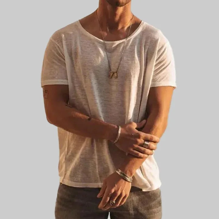 Man wearing a white lightweight crew neck T-shirt with relaxed fit, layered necklaces and bracelets visible.