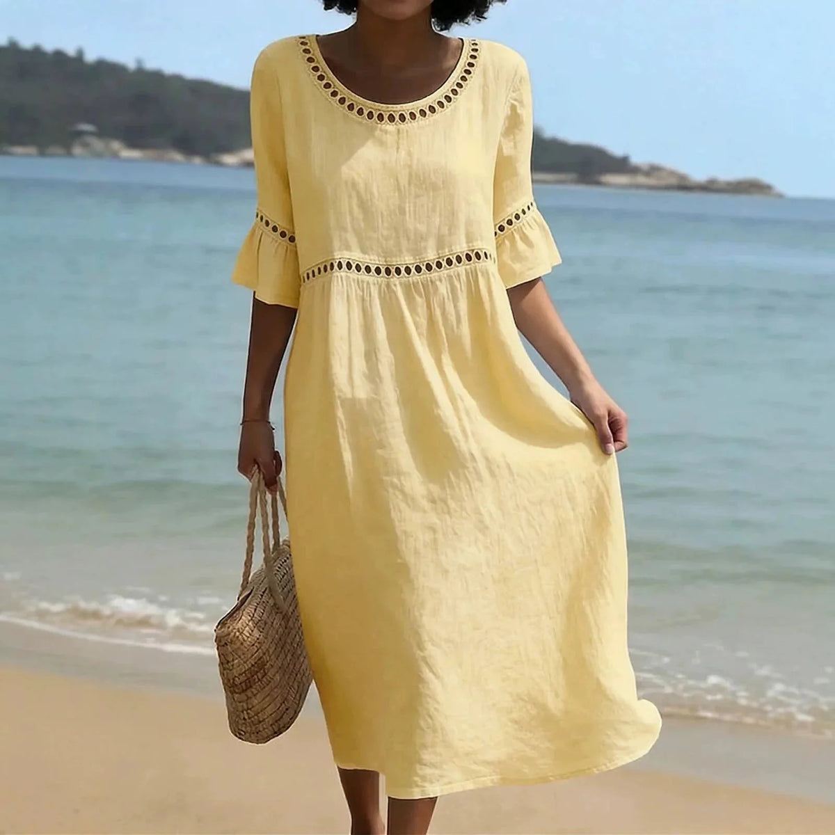 Woman walking on sand in a soft yellow midi dress featuring flared sleeves and a gathered waist