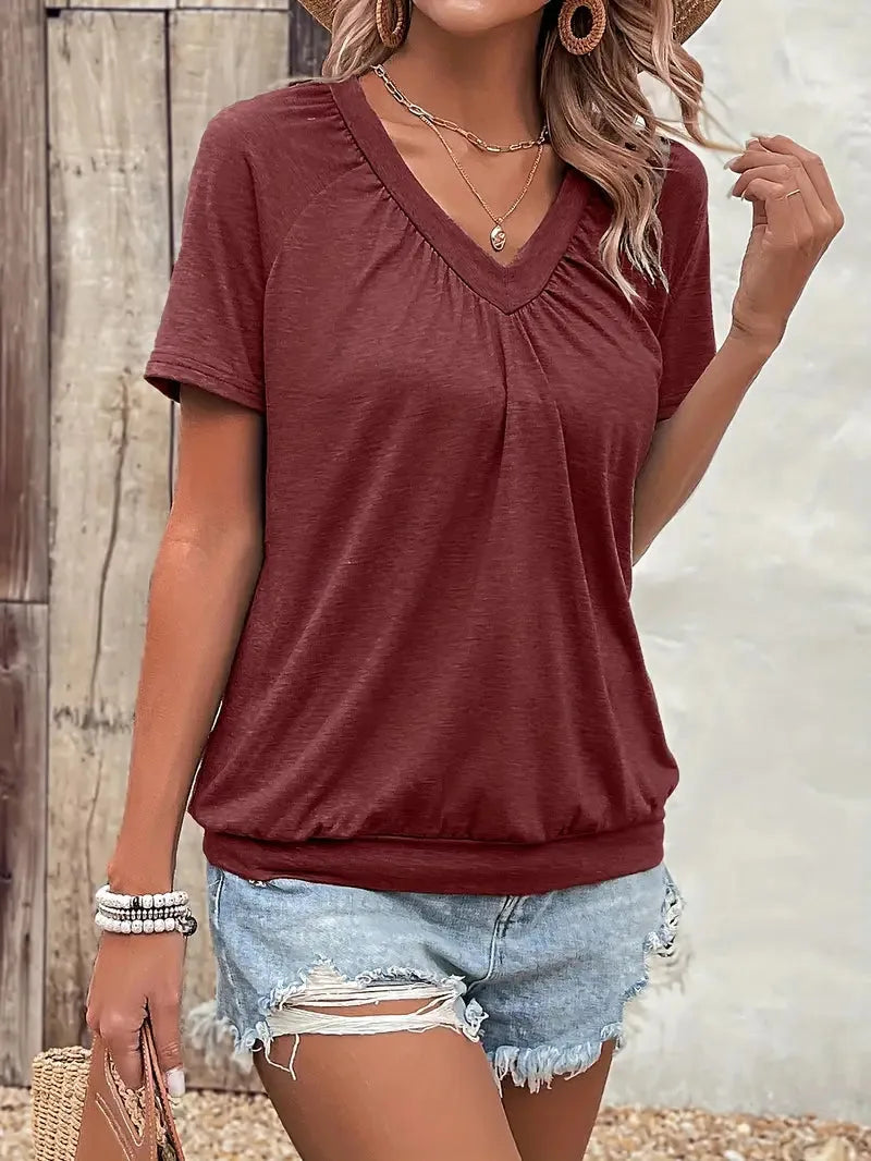 Front view of the T-shirt in a deep brick red tone, styled with denim shorts and layered necklaces