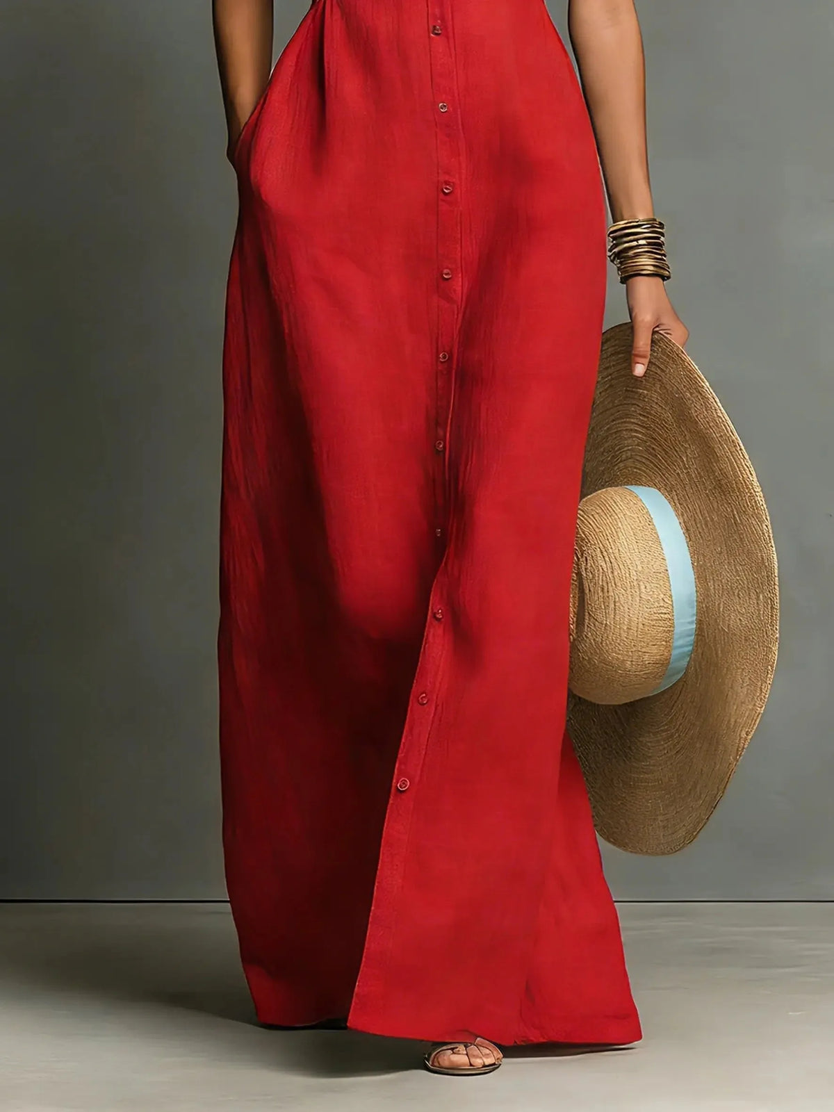 Close-up of the red maxi dress skirt and button placket from the waist down, paired with a straw hat