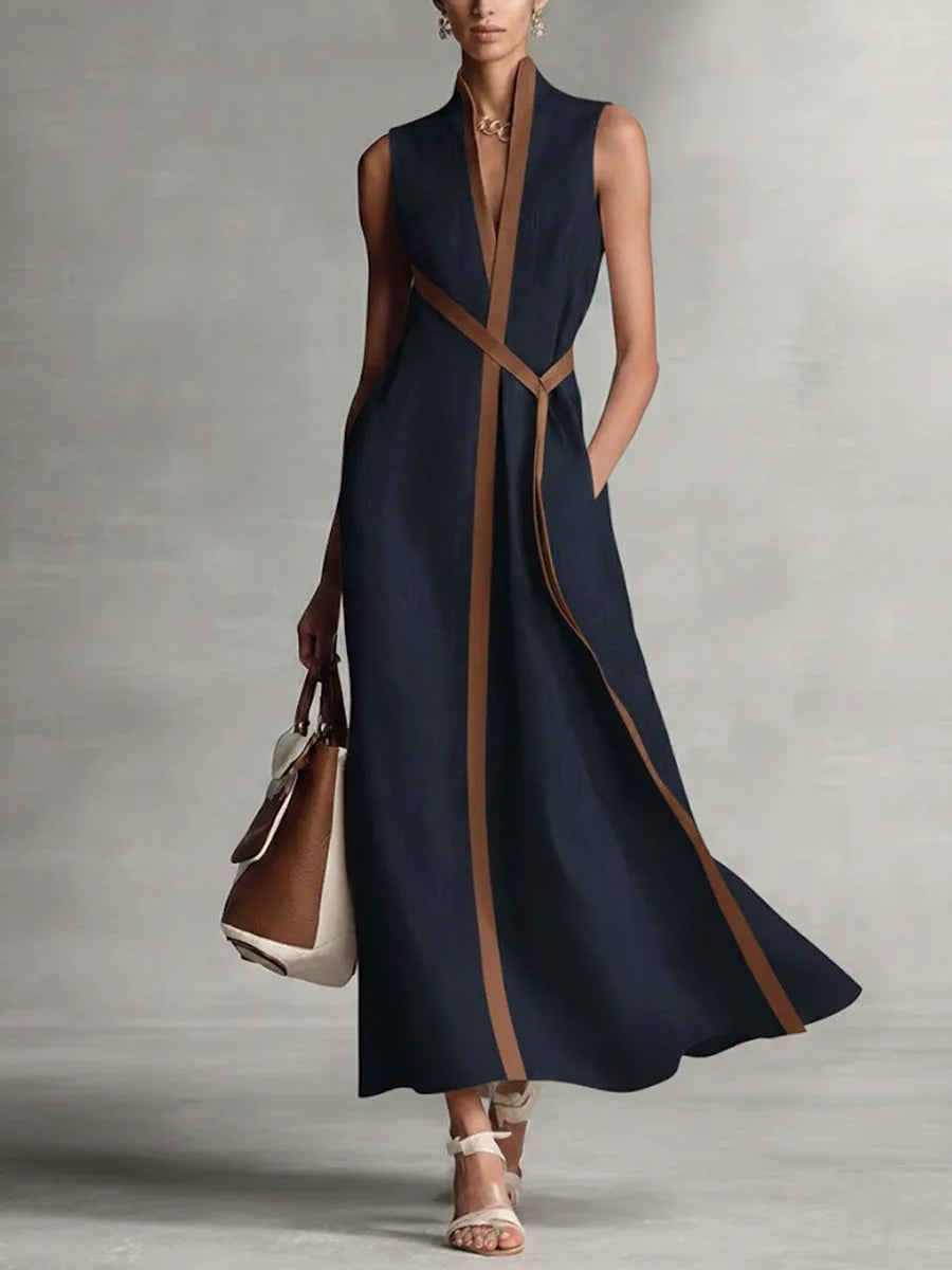 Navy sleeveless maxi dress with tan trim and mandarin collar, styled with a tan tote bag and nude heels