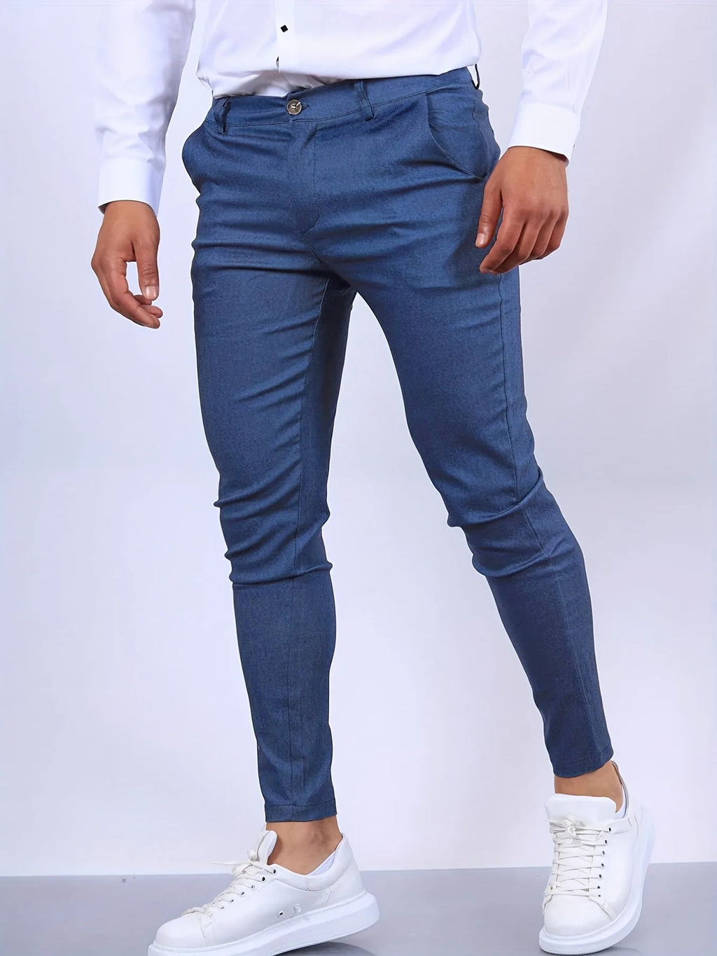 Side view of slim fit chino pants in blue twill, worn with white shirt and white sneakers