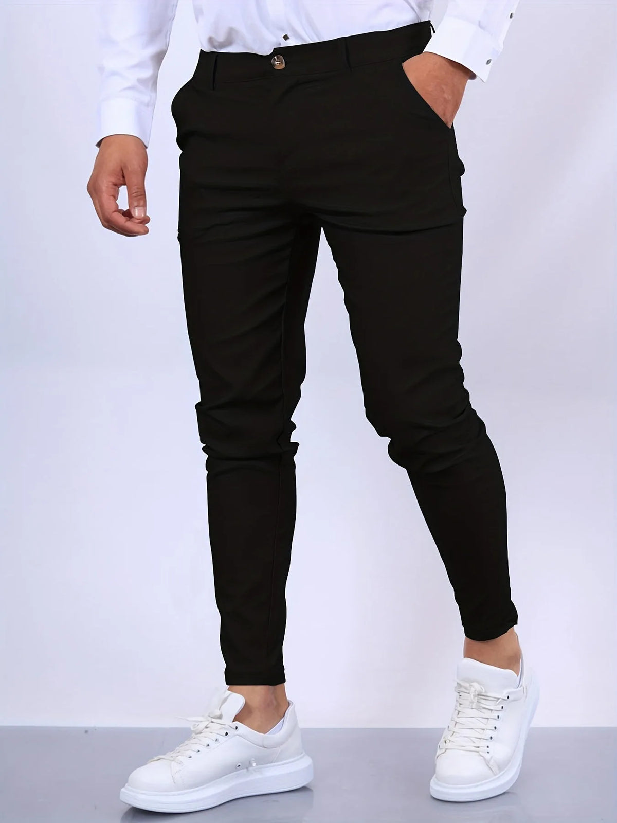 Side view of black slim fit chino pants with hand in pocket, paired with white shirt