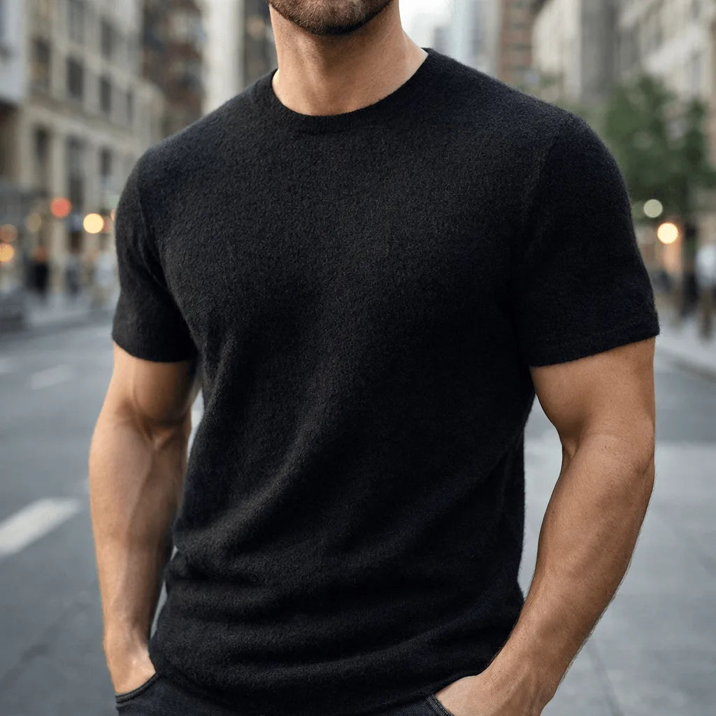 Man in a black short-sleeve knit tee with a relaxed fit, hands in pockets on an urban street