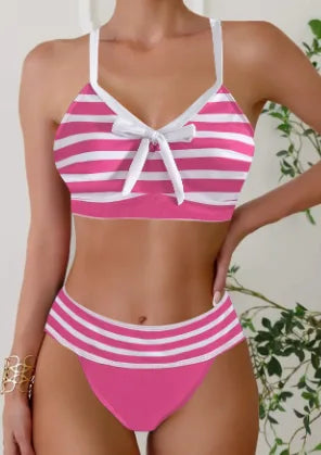 Pink and white striped bikini with bow-tie front detail and high-waisted bottoms, styled against a leafy backdrop.