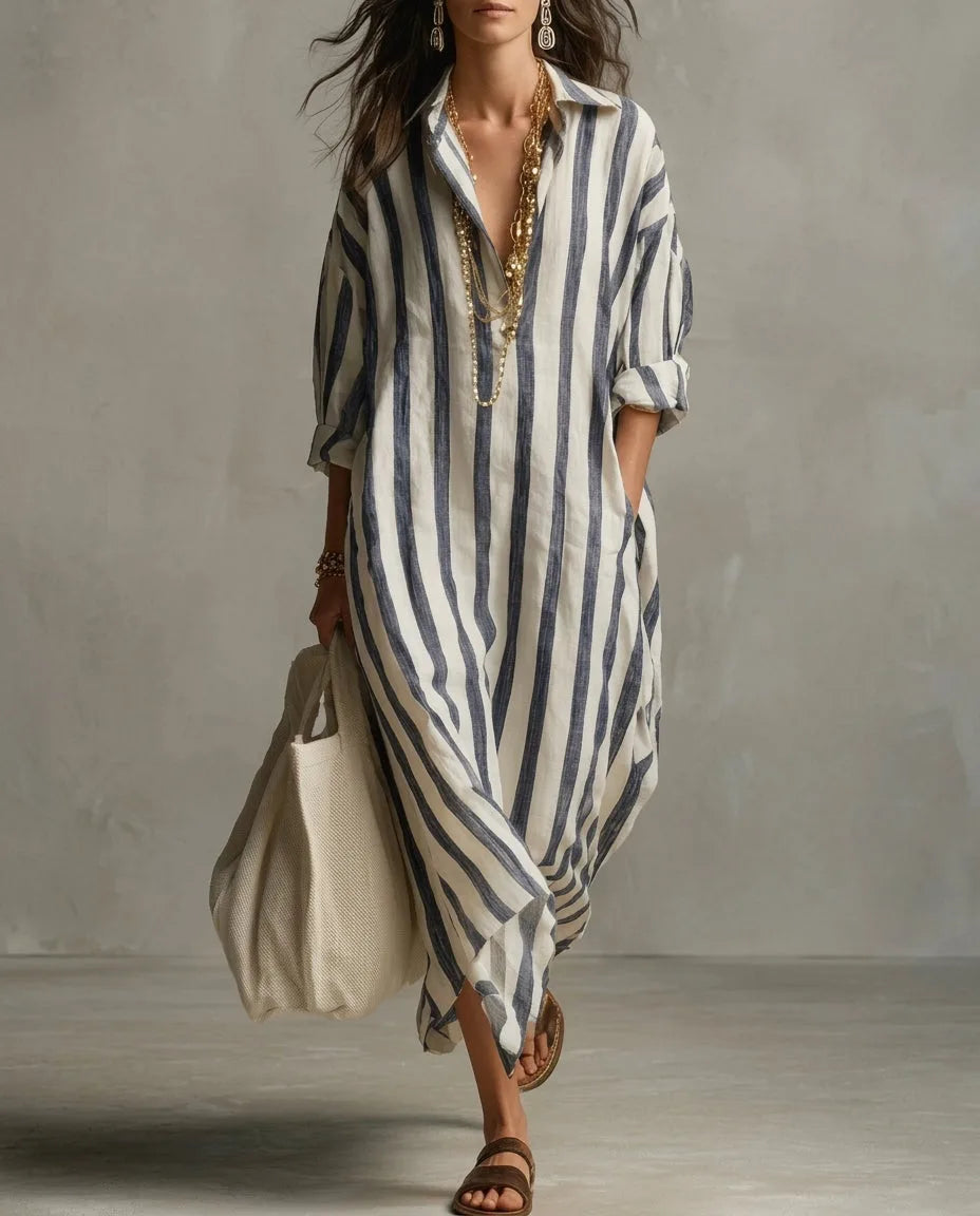 Woman walking in a blue and white striped linen maxi shirt dress with rolled sleeves and open collar