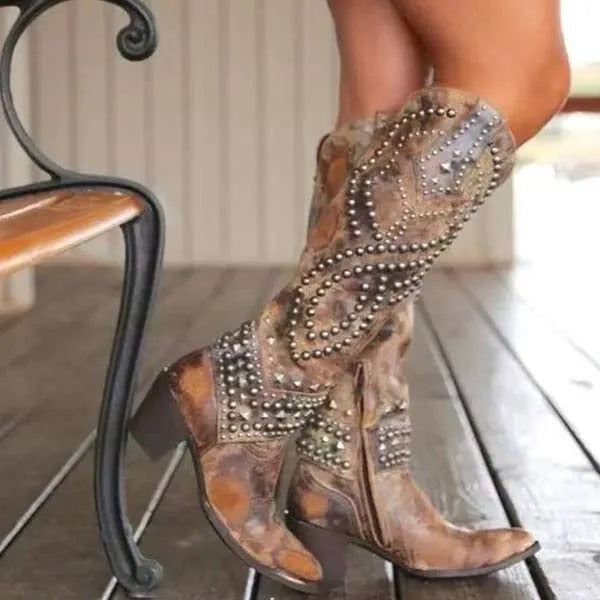 Side view of brown leather studded knee-high western boots with pointed toe and stacked block heel