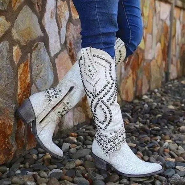 White leather studded knee-high western boots paired with skinny jeans, shown from the side