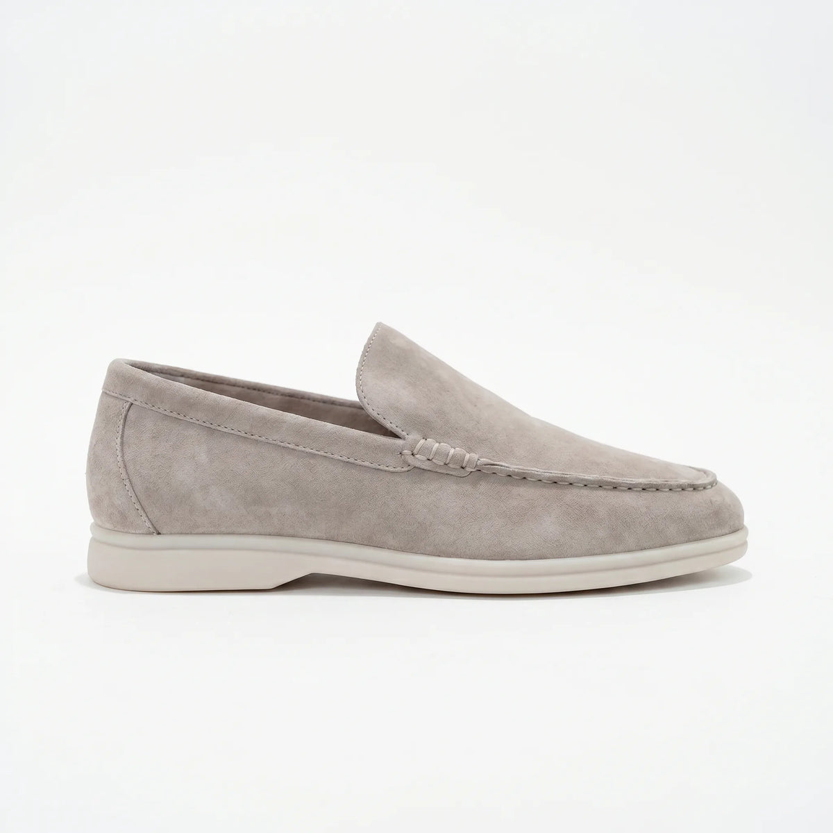 Side profile of a light grey suede loafer with white sole showing moc-toe stitching detail