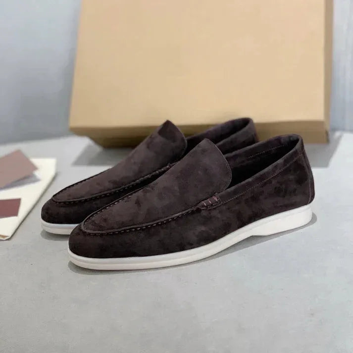 Pair of grey suede loafers shown from a three-quarter angle against a white backdrop