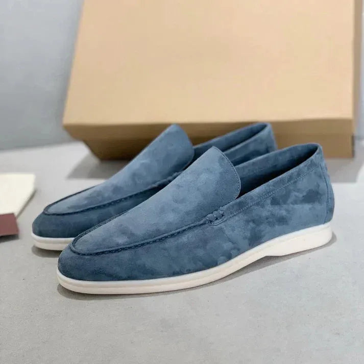 Side view of light brown suede loafers paired with their shoe box and dust bag