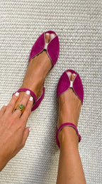 Overhead shot of magenta suede flat sandals with gold piping and ankle buckle strap