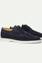 Pair of navy suede lace-up shoes shown side by side with contrast cream sole