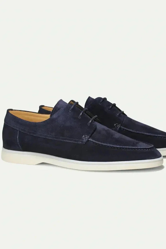 Pair of navy suede lace-up shoes shown side by side with contrast cream sole