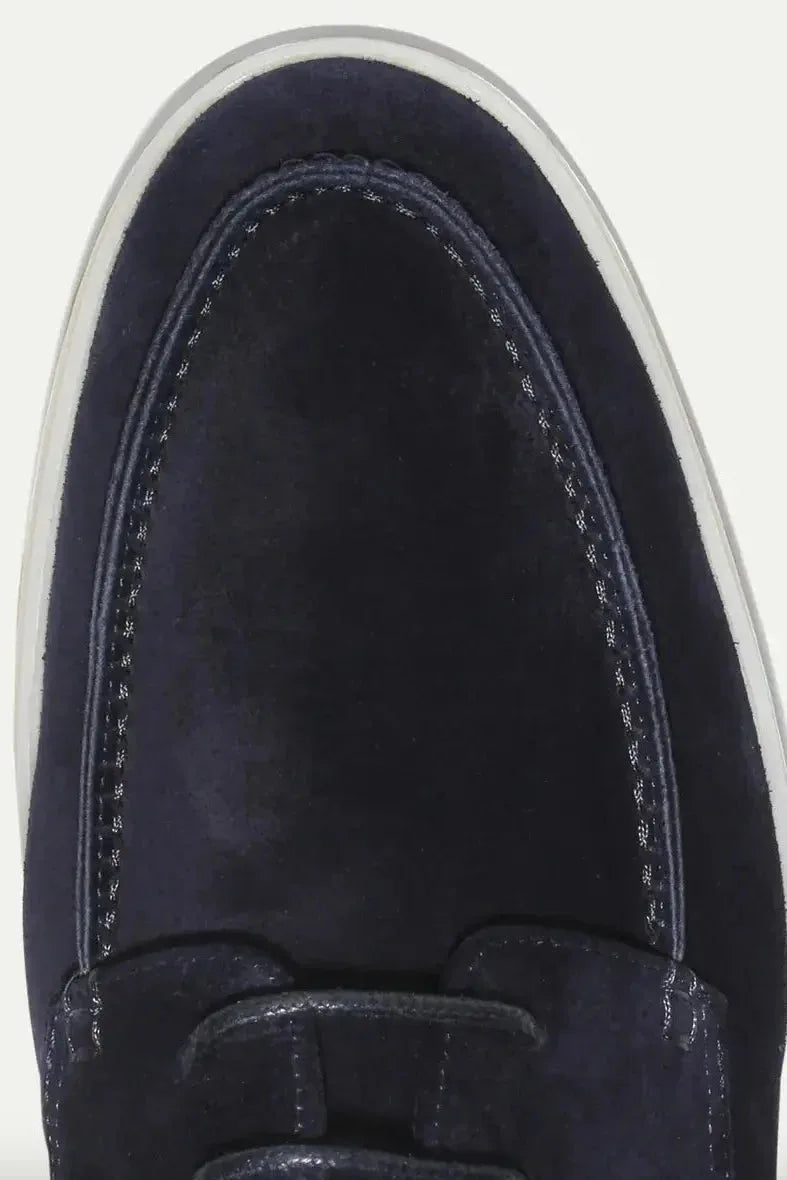 Close-up of the moc-toe stitching detail and suede texture on the navy shoe's toe
