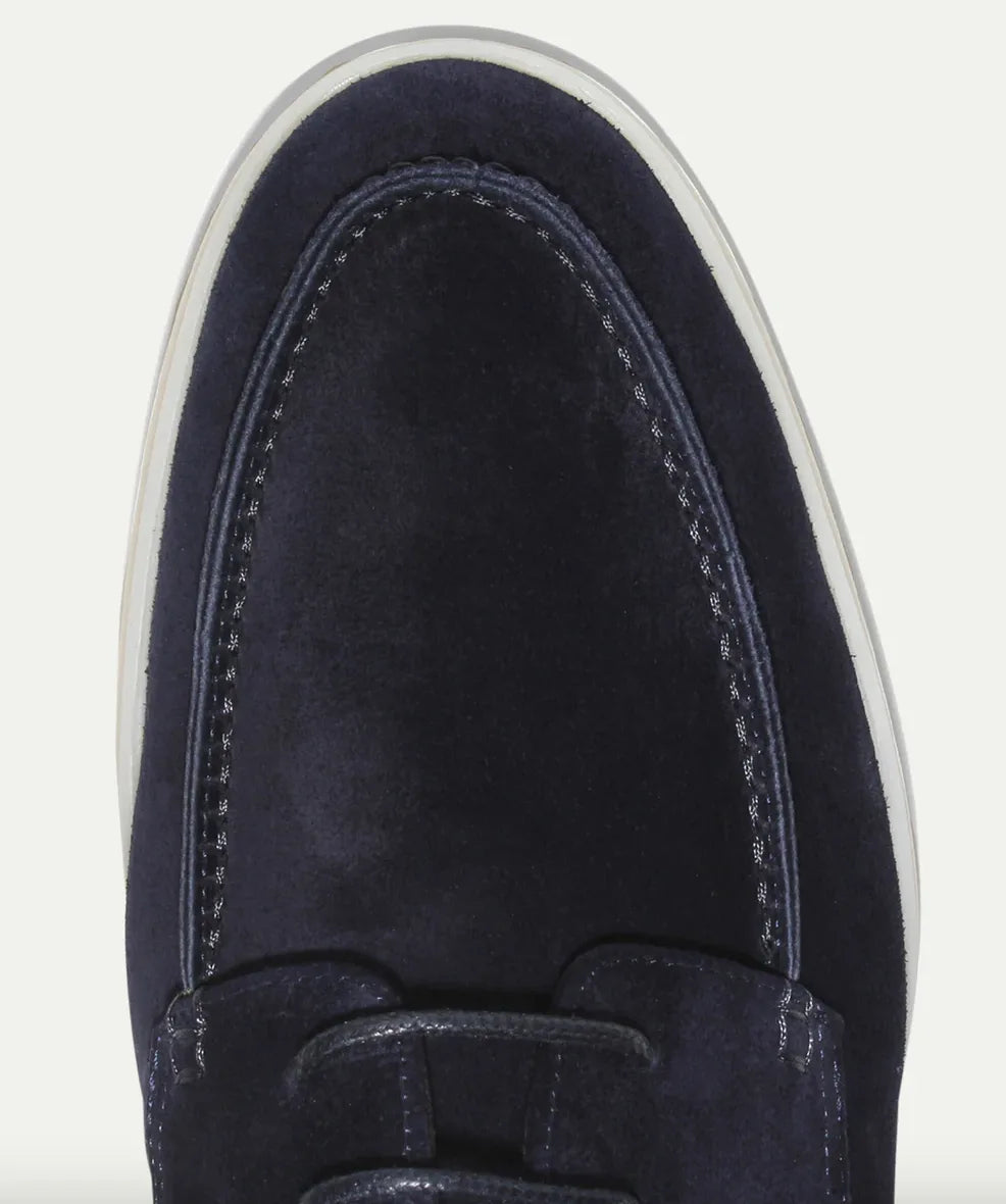 Close-up of the toe stitching and lace eyelets on a navy suede shoe