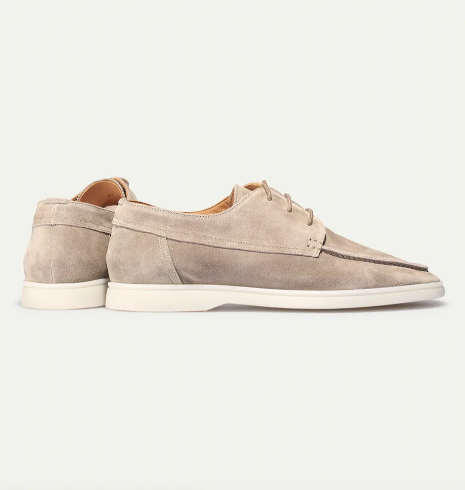 Angled view of beige suede lace-up shoes highlighting the tan leather lining and laces