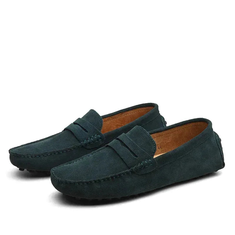 Pair of marine blue suede penny loafers shown at an angle with tan leather insole visible