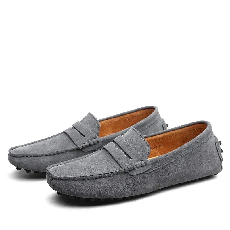 Grey suede penny loafers viewed from the side showing the studded rubber driving sole