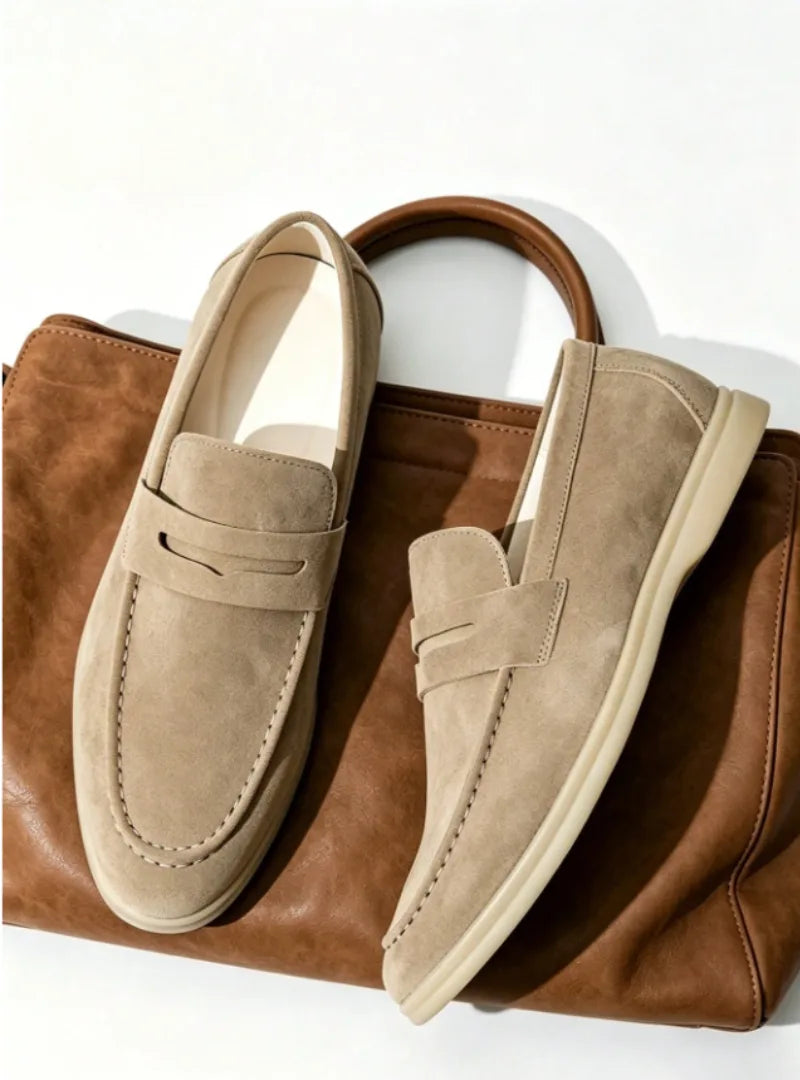 Side-by-side view of beige suede loafers with cream soles placed on a brown leather bag handle