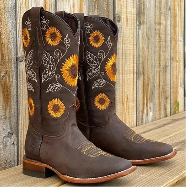 Dark brown knee-high western boots featuring embroidered sunflowers, leaves and swirling vine stitching on the shaft.