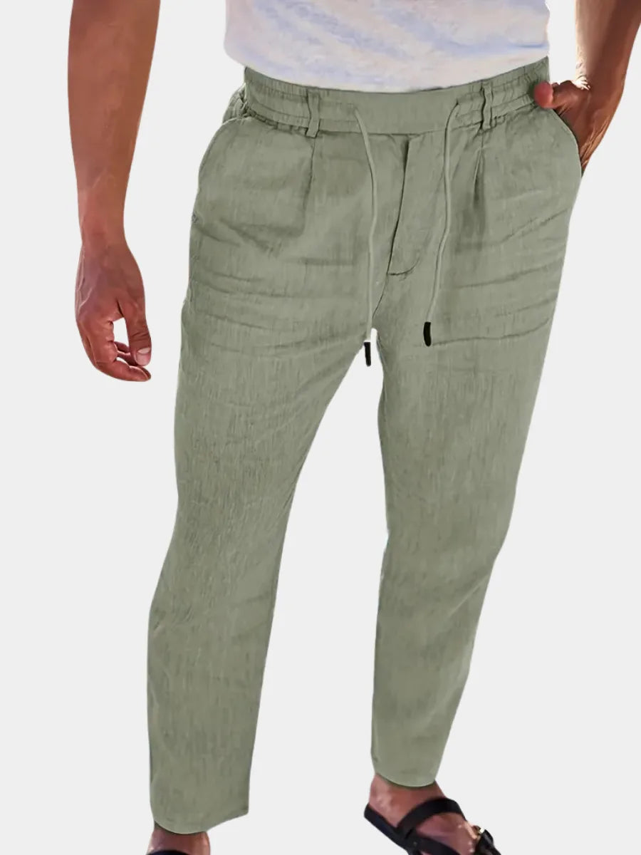 Close-up front view of sage green linen-blend pants with drawstring waist and pleated pockets, worn with sandals
