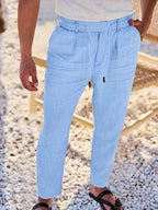 Front view of sky blue linen-blend trousers showing elastic drawstring waist and side pockets on a man walking outdoors