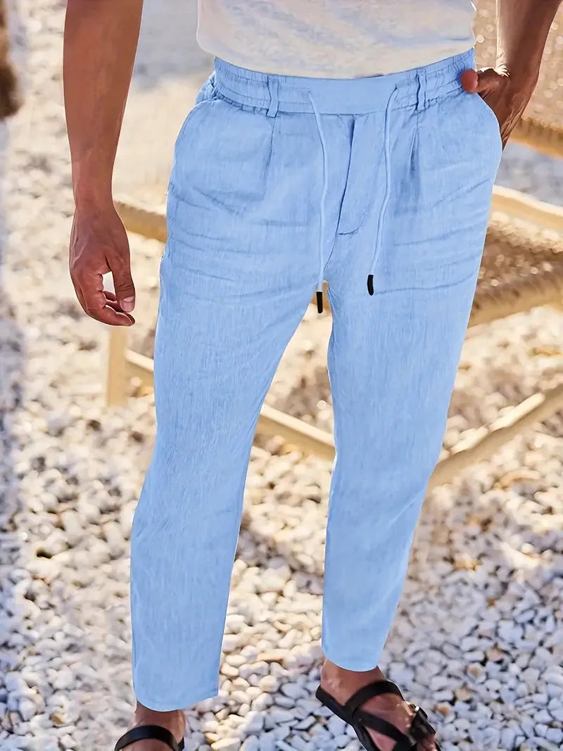 Front view of sky blue linen-blend trousers showing elastic drawstring waist and side pockets on a man walking outdoors