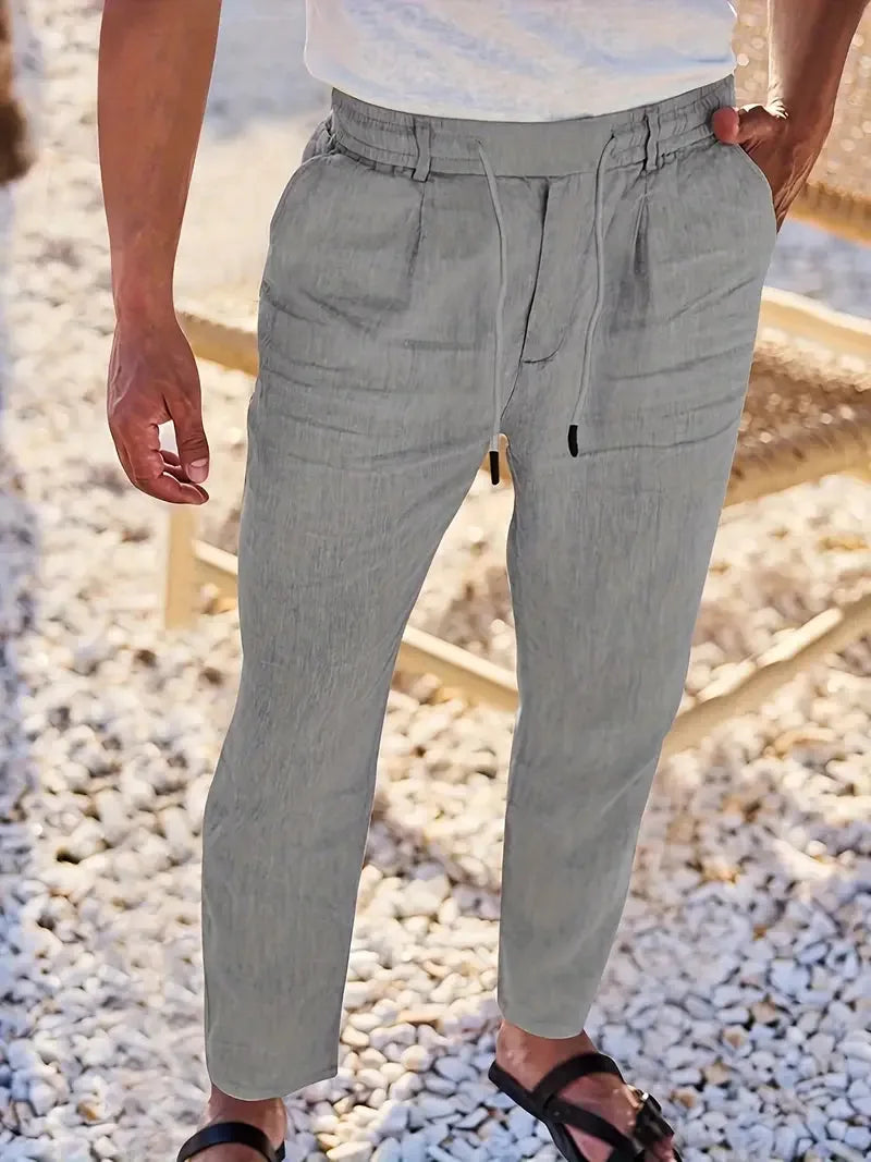 Light grey linen-blend trousers with elastic waistband and drawstring, paired with black slide sandals