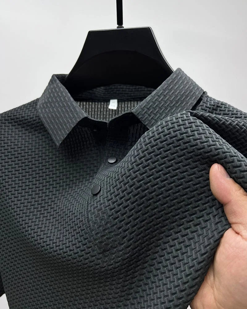 Close-up of dark grey textured woven polo shirt on hanger, showing basket-weave fabric and button placket