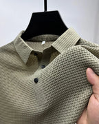 Beige textured polo shirt close-up, showing woven collar, button placket and sleeve fabric held by hand