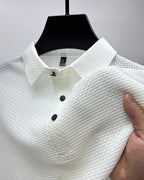 White textured polo shirt detail shot, showing collar, button placket and subtle woven pattern on sleeve